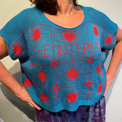 A blue knitted shirt with a red graphic pattern and the text 'THE INTERKNIT' displayed on the front.